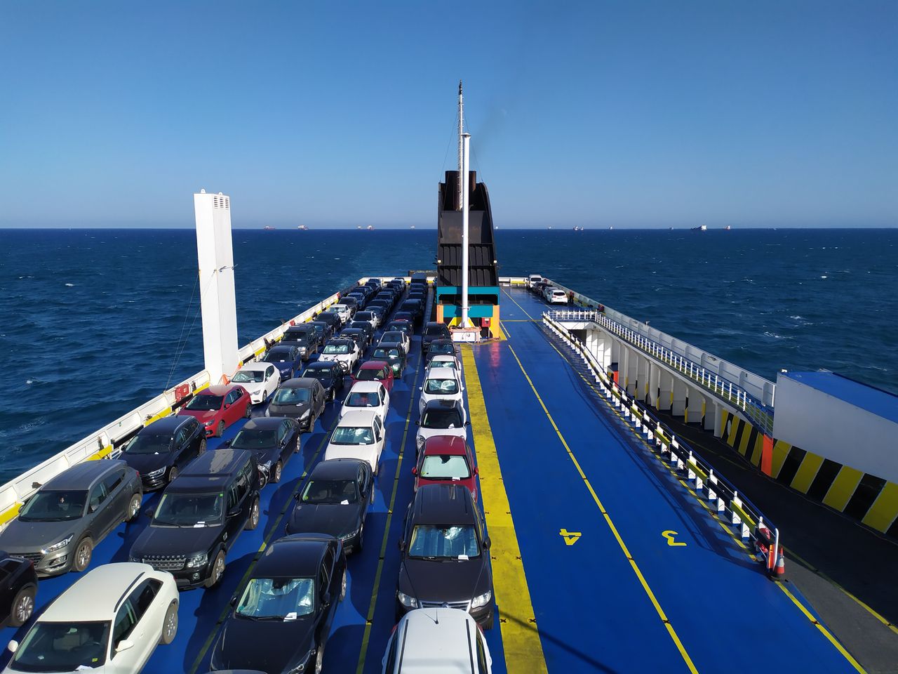 A sea ferry carrying cars across the ocean on a clear day, depicting maritime travel.