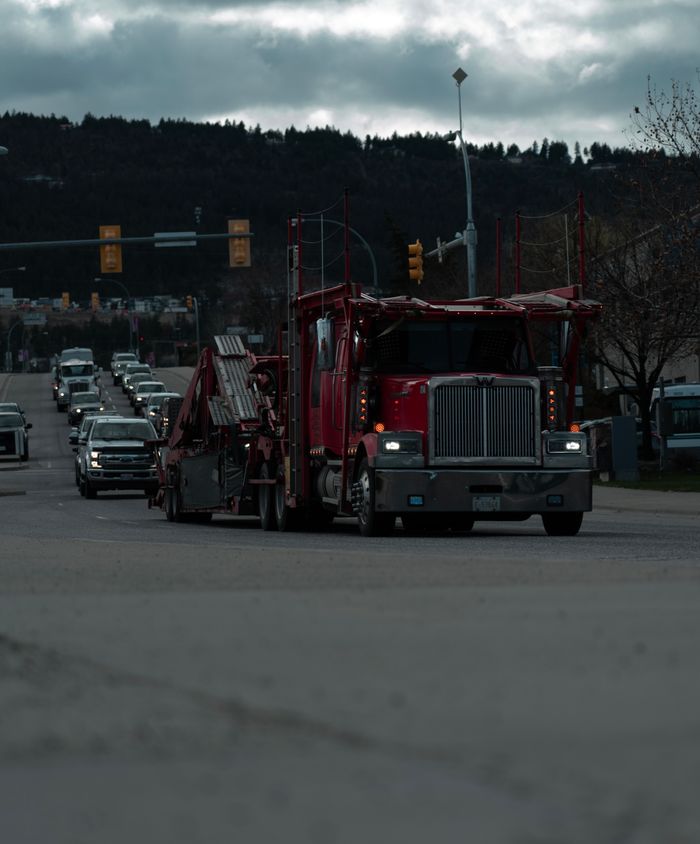 Street scene with trucks and cars under cloudy skies, highlighting urban traffic and transportation.