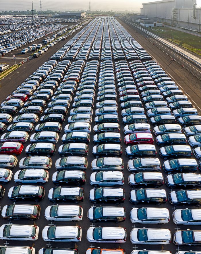 From above of many modern new automobiles placed on asphalt near factory in daytime